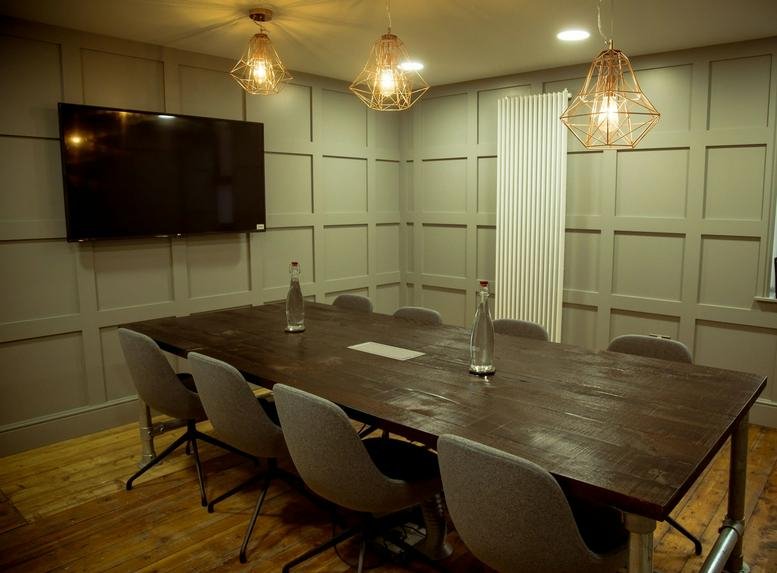 Spacious meeting room at WorkSmart Hub, 12-14 Shaw’s Road, Altrincham, with wood-paneled walls and a large table.