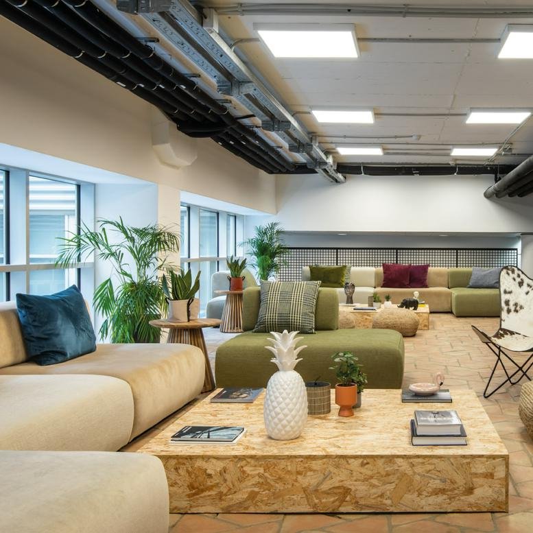 Spacious communal lounge with green modular seating and a wooden coffee table at World Trade Center Almeda Park.