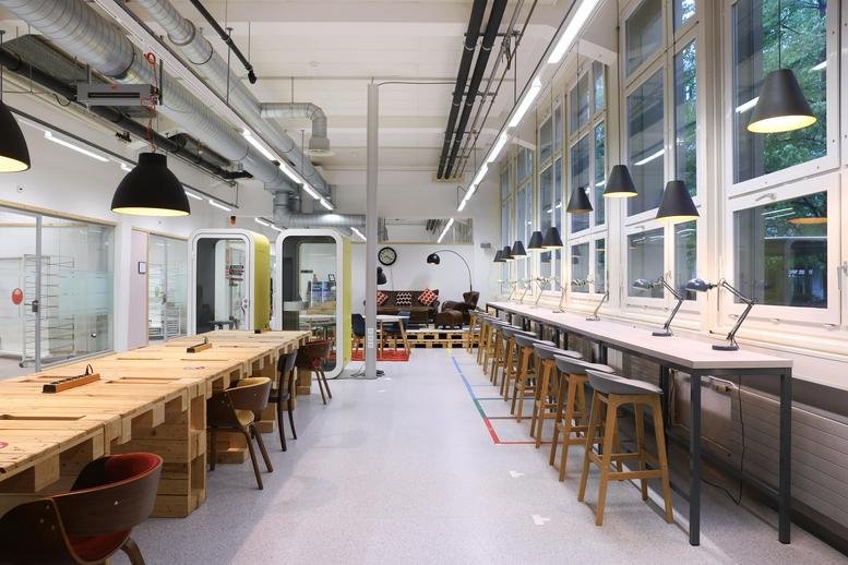 Spacious industrial-style coworking area at Zählerweg 5 & 7, Freiruum, Zug with wooden pallet tables and tall windows.