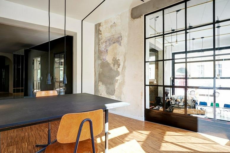 Spacious communal dining area at Zehdenicker Strasse 1 featuring warm wood floors and large glass partitions.