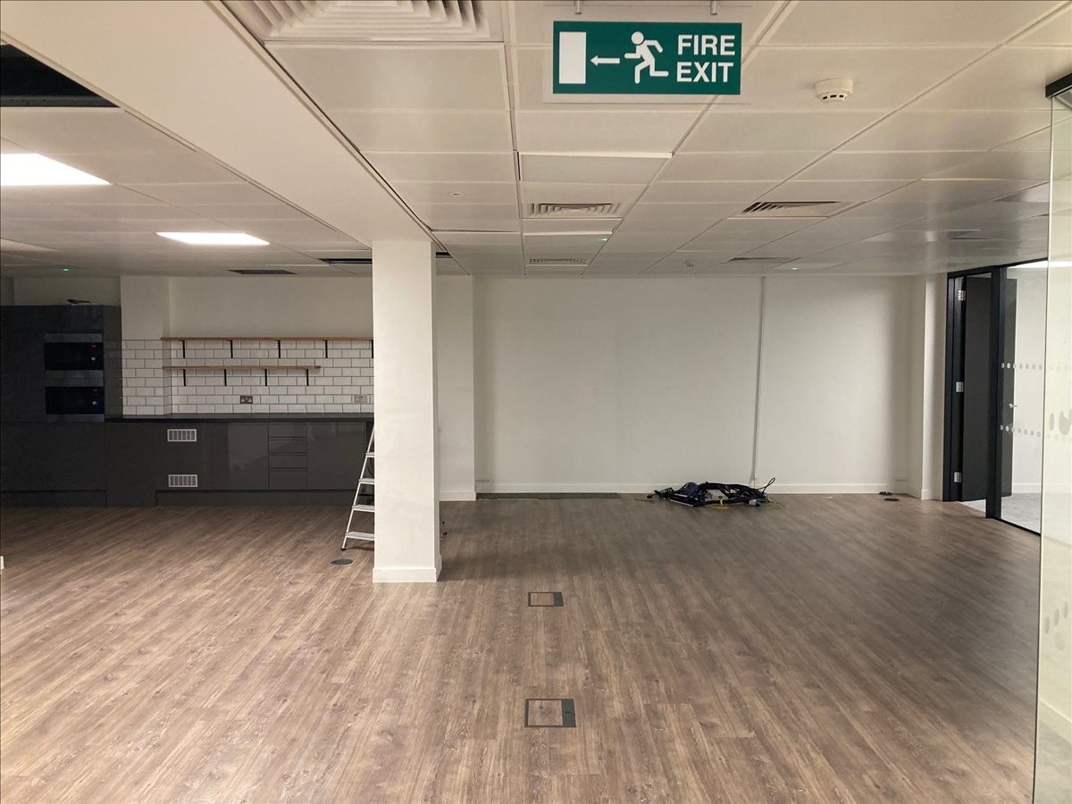 Spacious communal kitchen and breakout area with wood-effect flooring and modern cabinetry.