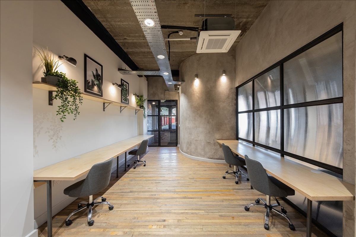 Spacious coworking area at Quay Level, St. Peters Wharf, Unit 16 with long wooden desks and industrial ceilings.