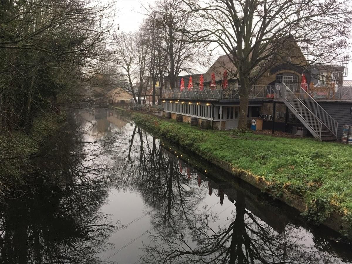 Exterior view of The 1929 Shop, Merton Abbey Mills building alongside a tranquil canal.
