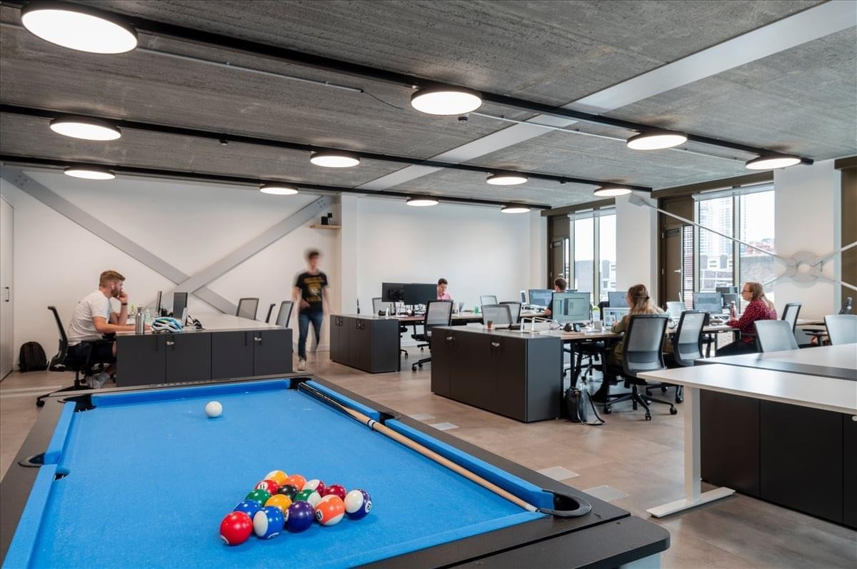 Bright workspace at 3rd Floor, Verse Building with desks and a blue pool table for employee recreation.