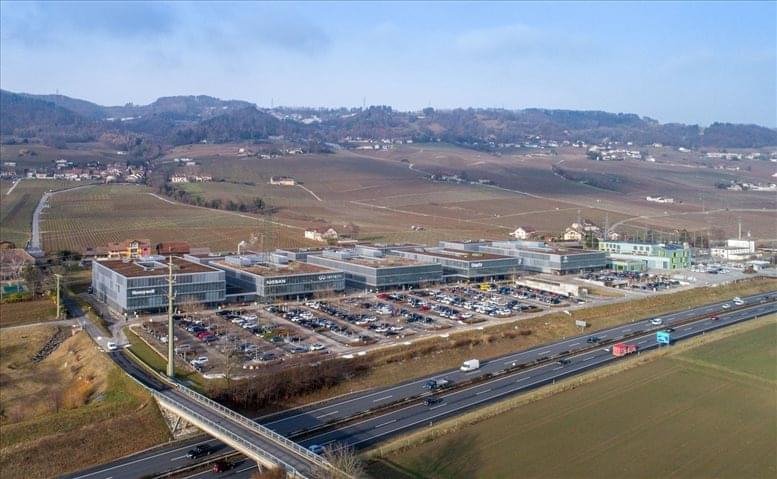 Aerial view of the modern commercial campus at ZA La Pièce 1, Rolle, Switzerland near the highway.