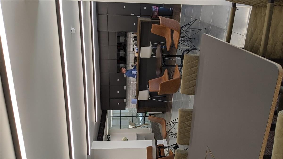 Communal lounge area with leather chairs and bright linear ceiling lights.