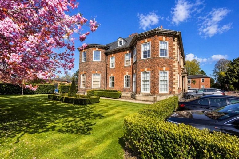 Exterior view of the historic red brick facade of The Hall, Lairgate with pink cherry blossoms.