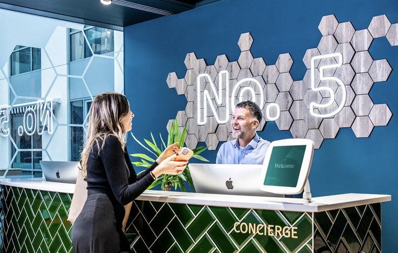 Modern reception desk at The Heights in Weybridge with green tile patterns and honeycomb wall art.