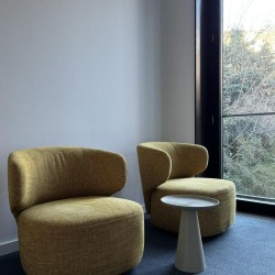 Bright corner lounge area with two textured yellow armchairs and a small white side table.