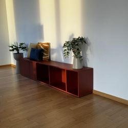 Reddish-brown shelving unit used for storage and decor in a room with light wood flooring.
