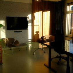 Conference room at sunset with a dark table, black office chairs, and long shadows.