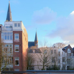 City view from a window showing traditional brick architecture and a church spire.