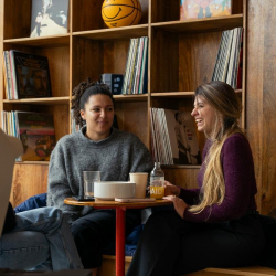 Cozy common area with two women chatting near a wooden shelf filled with vinyl records.