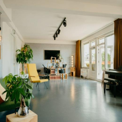 Spacious creative studio with a piano, acoustic guitar, and comfortable seating.