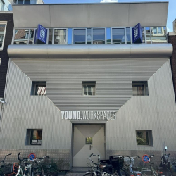 Contemporary building facade with signage and bicycles in front.