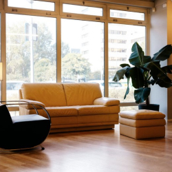 Bright office breakout space with comfortable leather seating and floor-to-ceiling windows.