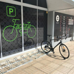 Exterior bicycle rack area with a parked bike next to windows with green branding.