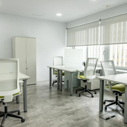 Bright open-plan workspace with multiple white desks and lime green ergonomic chairs.
