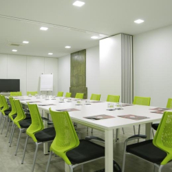 Large conference room with a long white table, lime green chairs, and a wall-mounted TV.