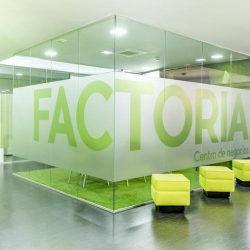 Glass-walled meeting pod with yellow cube seating and large green frosted lettering.