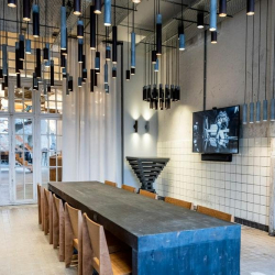 Boardroom with a long dark table under vertical pendant lights.