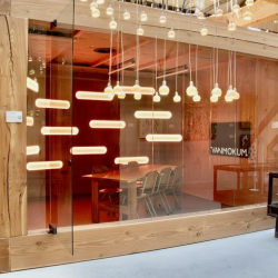 Meeting room viewed through glass with glowing horizontal light fixtures.