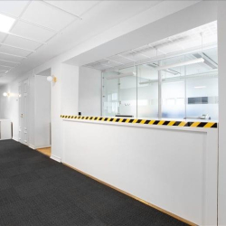 Sleek office hallway with glass partitions and dark carpeting.