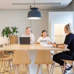 Individuals collaborating at a light-colored communal table in a bright workspace.
