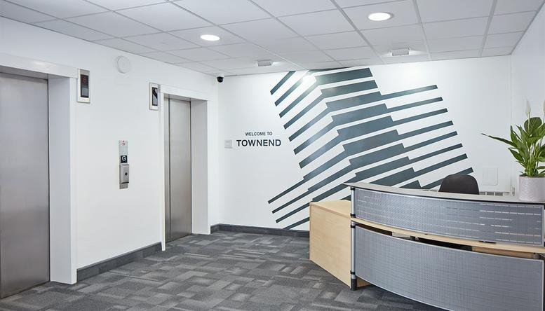 Reception area at Townend House, Wisemore with modern geometric wall art and elevator access.
