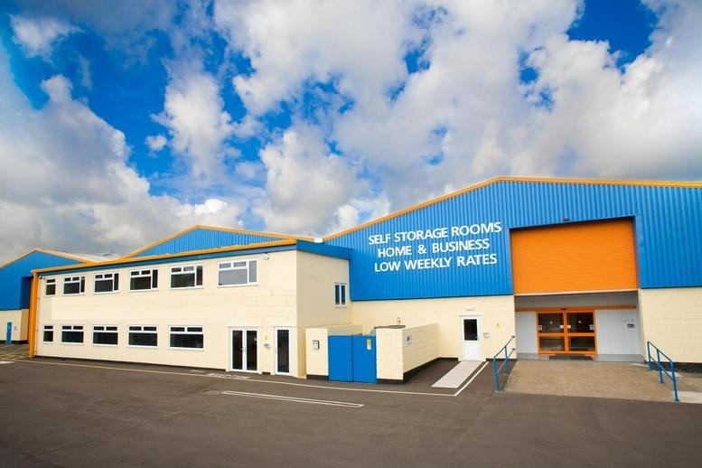 Exterior view of the blue and cream Unit 16 Leeway Industrial Estate building under a bright cloudy sky.
