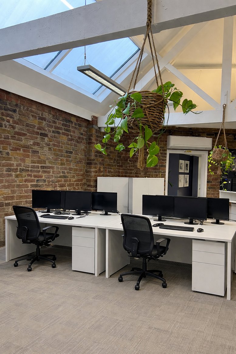 Open-plan workspace at Unit 6, The Couryard, Lynton Road with vaulted ceilings and hanging plants.