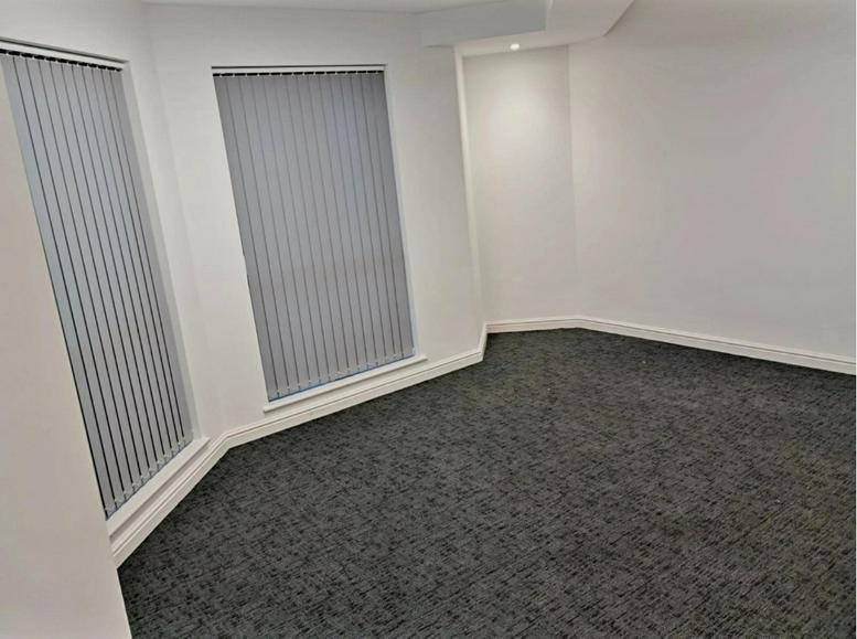Small private office with grey carpet and vertical blinds on the windows.