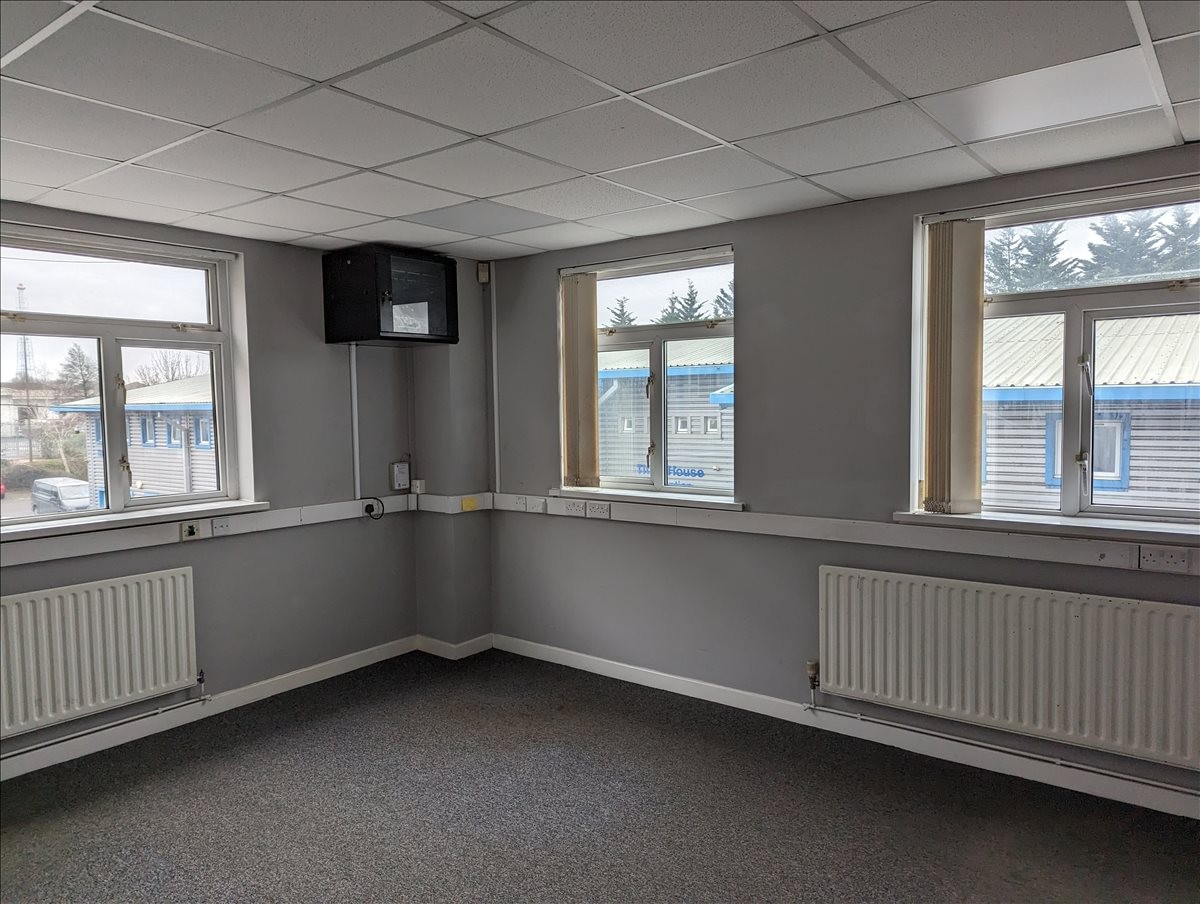 Bright, empty corner office at Bute House, Cardiff Bay Business Centre with grey walls and large windows.