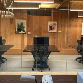 Modern glass-walled office workspace at Meeuwenlaan 126B with ergonomic chairs and warm wood paneling.. Click for details.